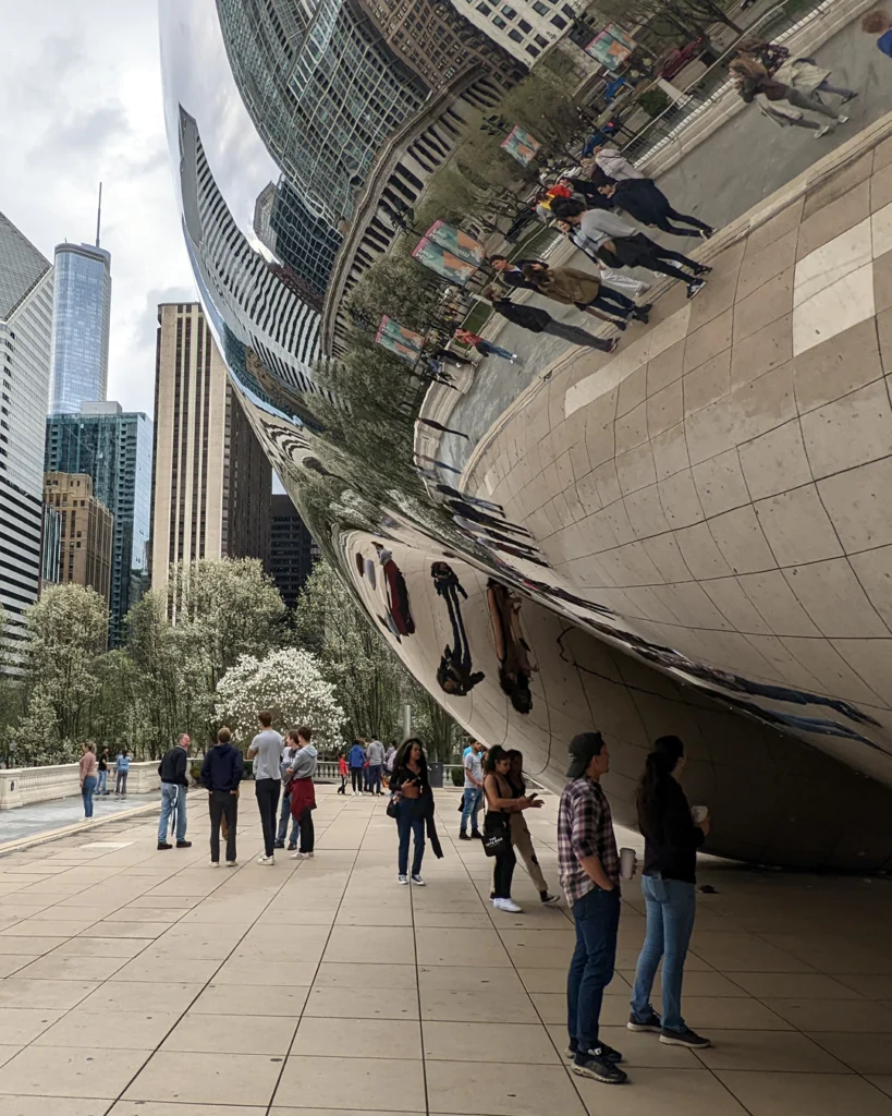 Turistas mirando sus reflejos en Cloud Gate, comunmente llamado The Chicago Bean, el Frijol de Chicago.